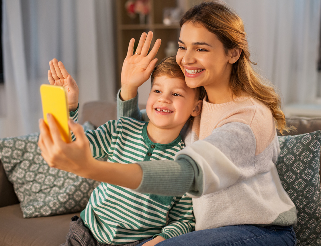 Mother and son waving at a mobile phone