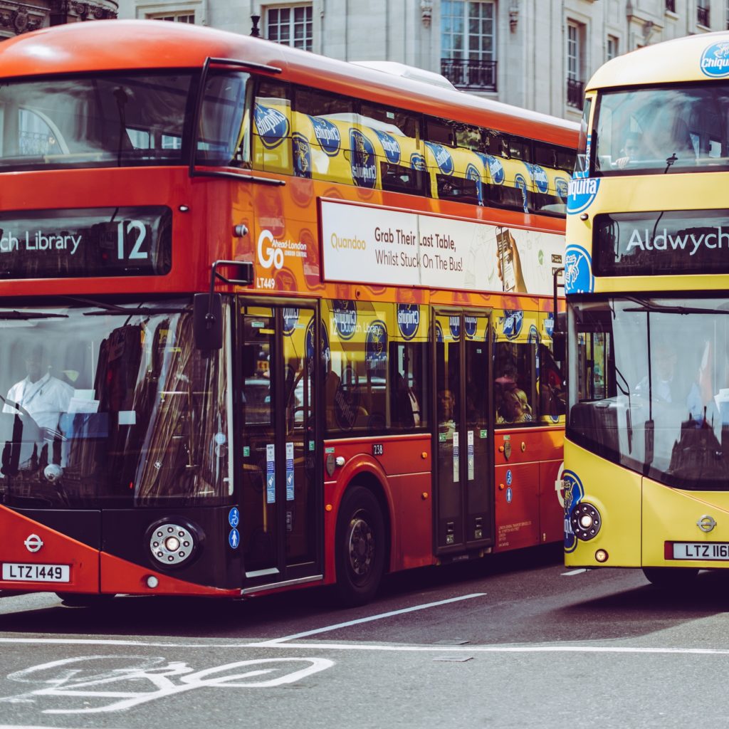 Photo showing two double decker london busses, one is red, and one is yellow