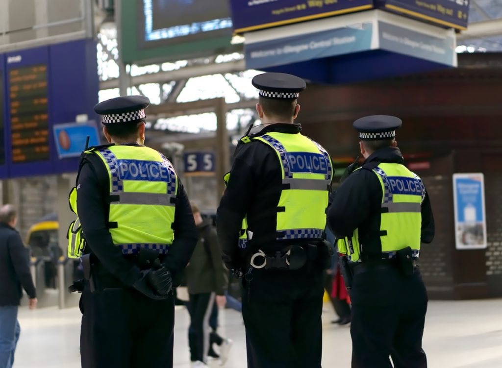 Three public safety British Police Officers on duty at a train station